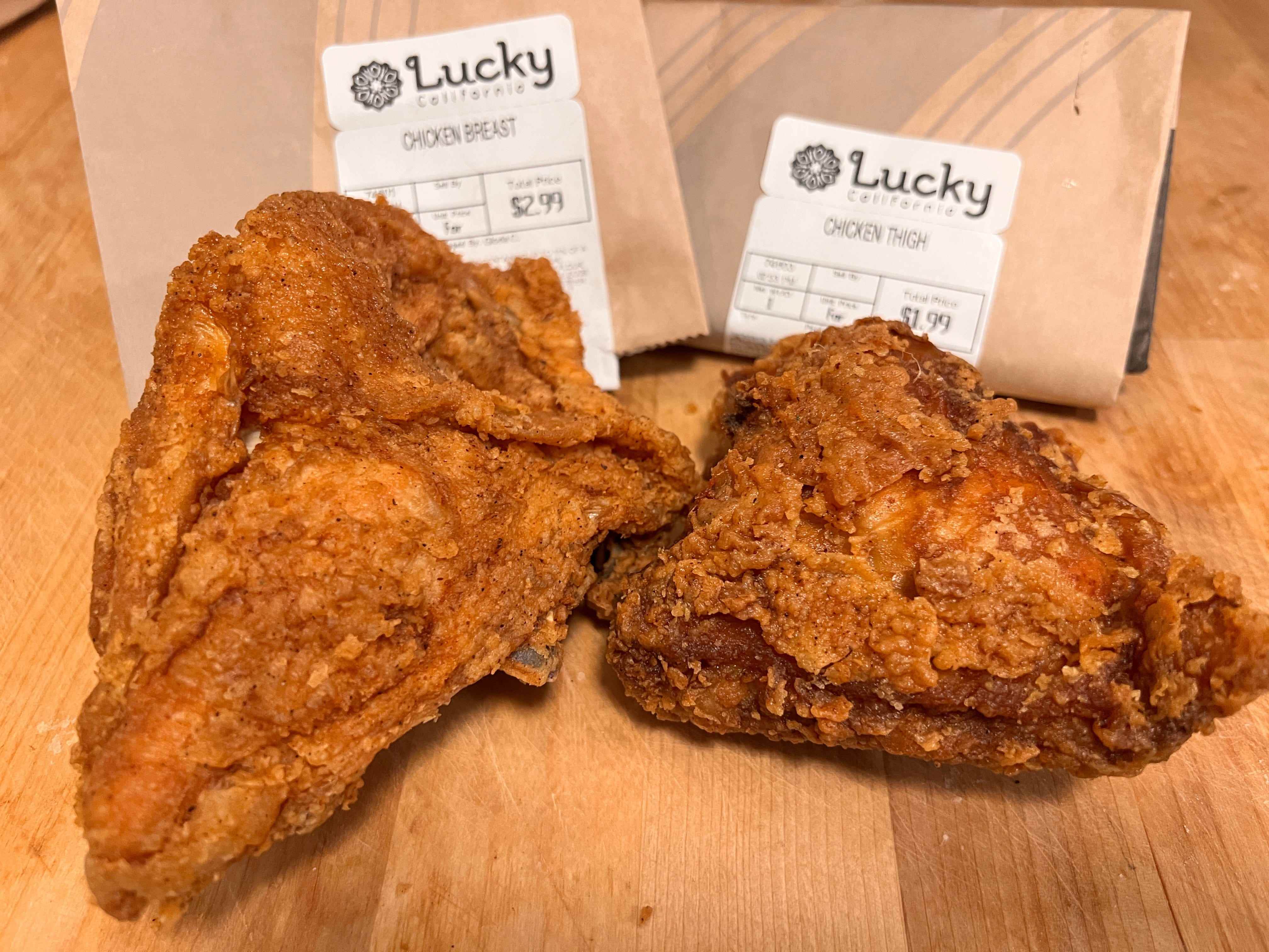 Gebratene Hähnchenbrust und -keule vor braunen Lucky's-Supermarkttüten