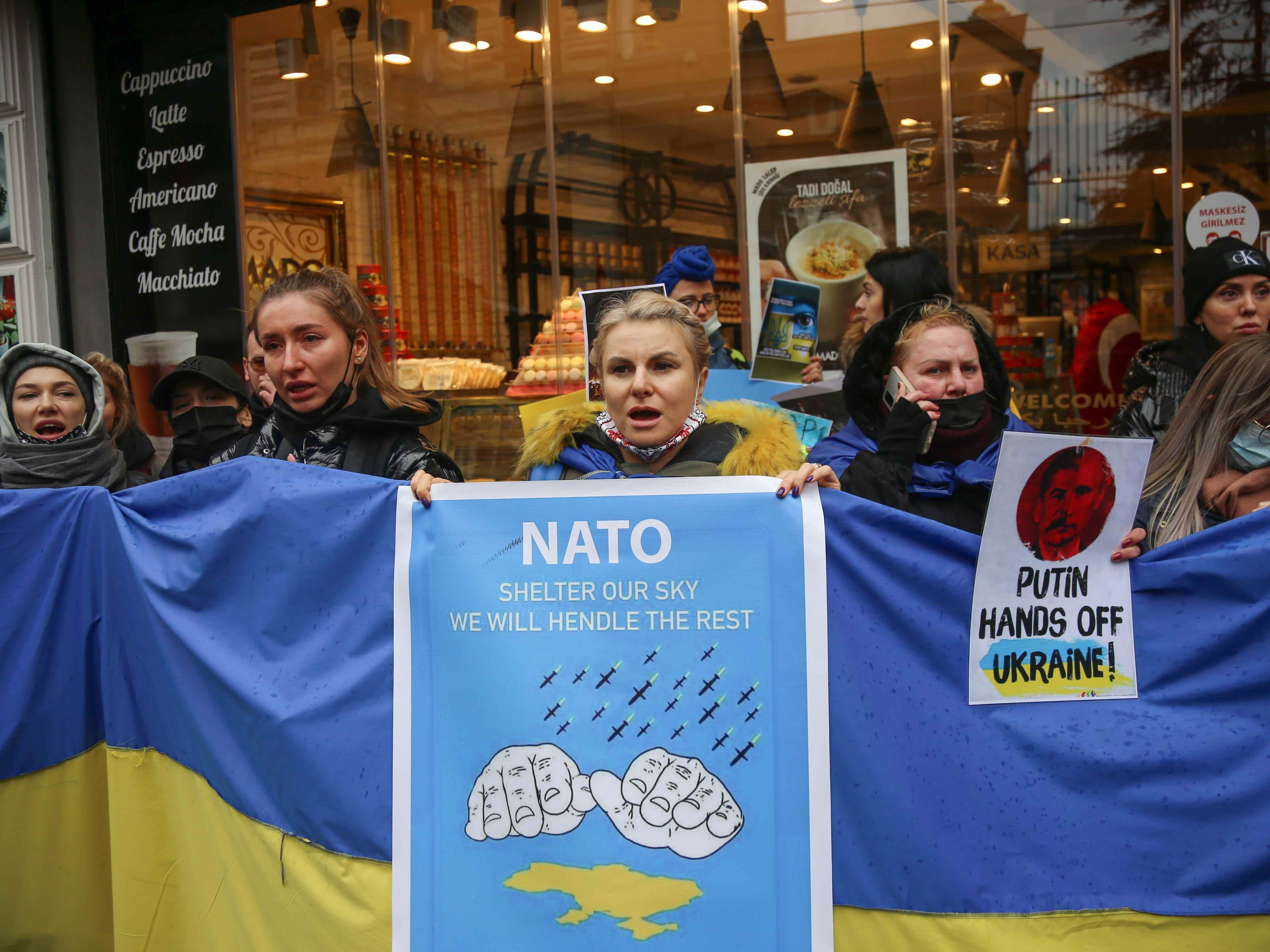 Demonstranten halten ein Schild mit der Aufschrift „Putin Hände weg von der Ukraine“