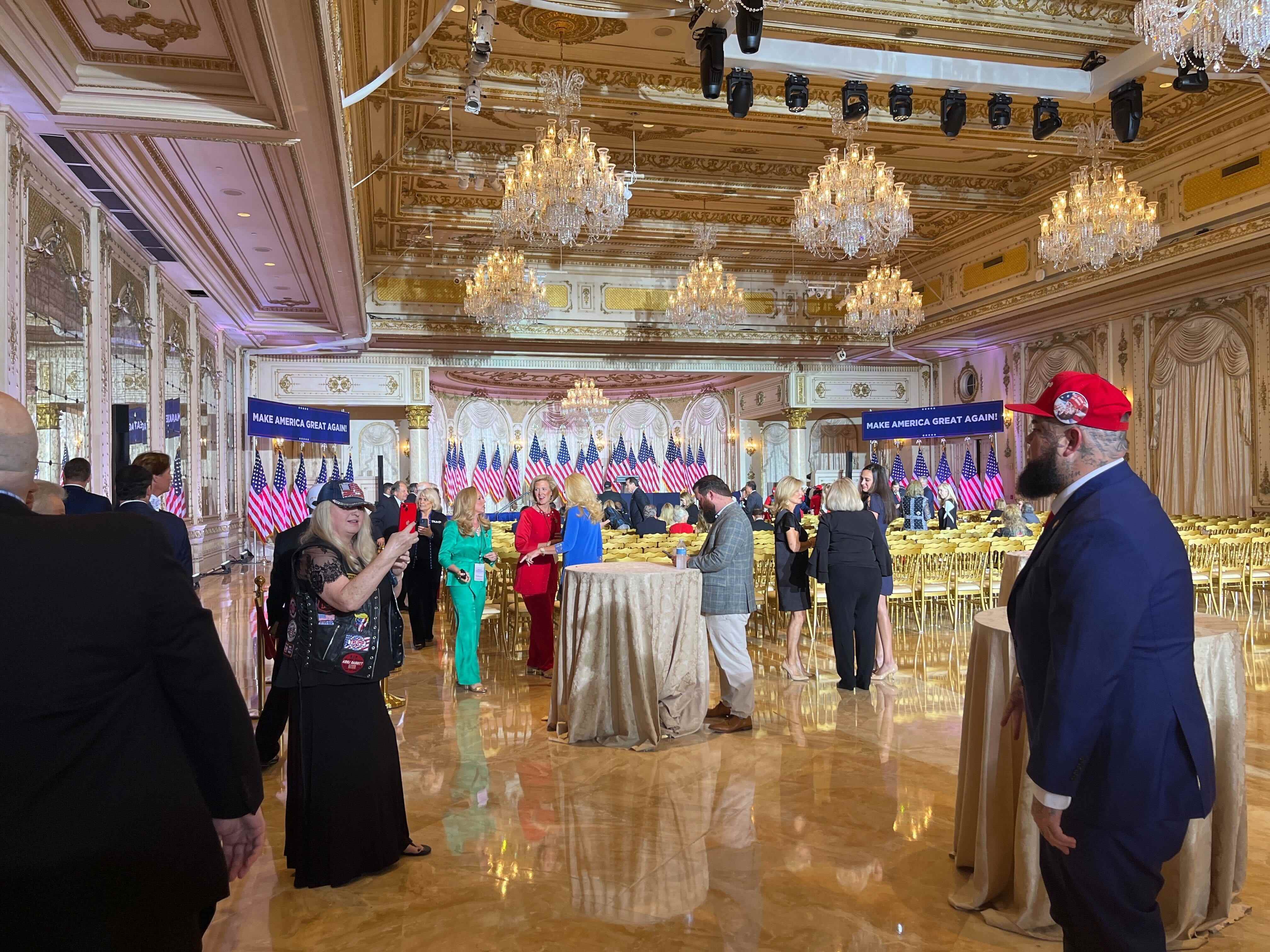 Eine Menschenmenge in Anzügen und Kleidern in einem goldenen Ballsaal