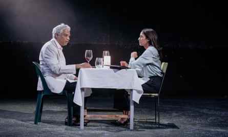 Siva und Lakshmi sitzen sich an einem Tisch für zwei Personen gegenüber, der für eine teure Mahlzeit gedeckt ist