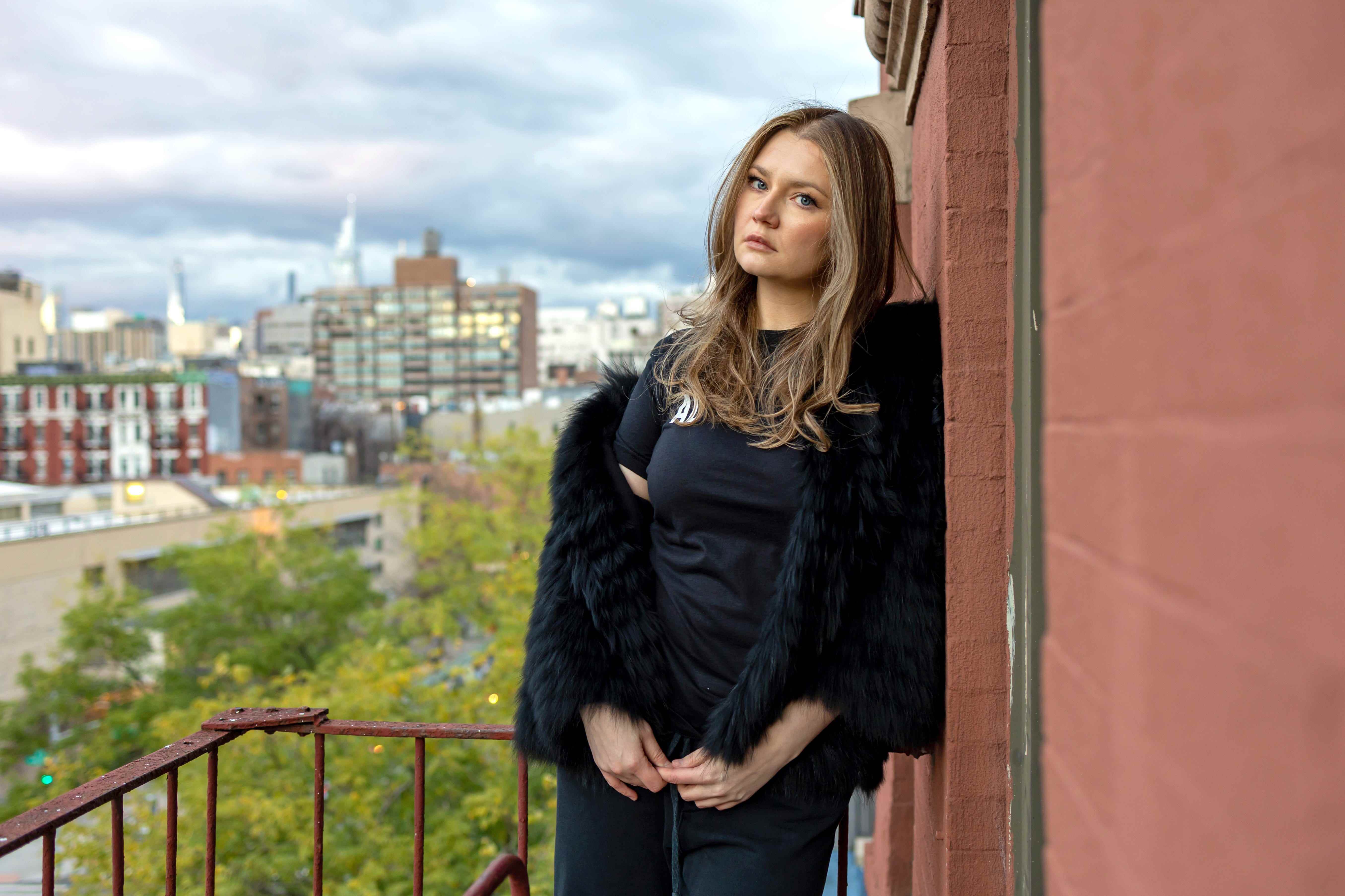 Anna Sorokin/Anna Delvey posiert für ein Foto vor einer Backsteinmauer in New York City