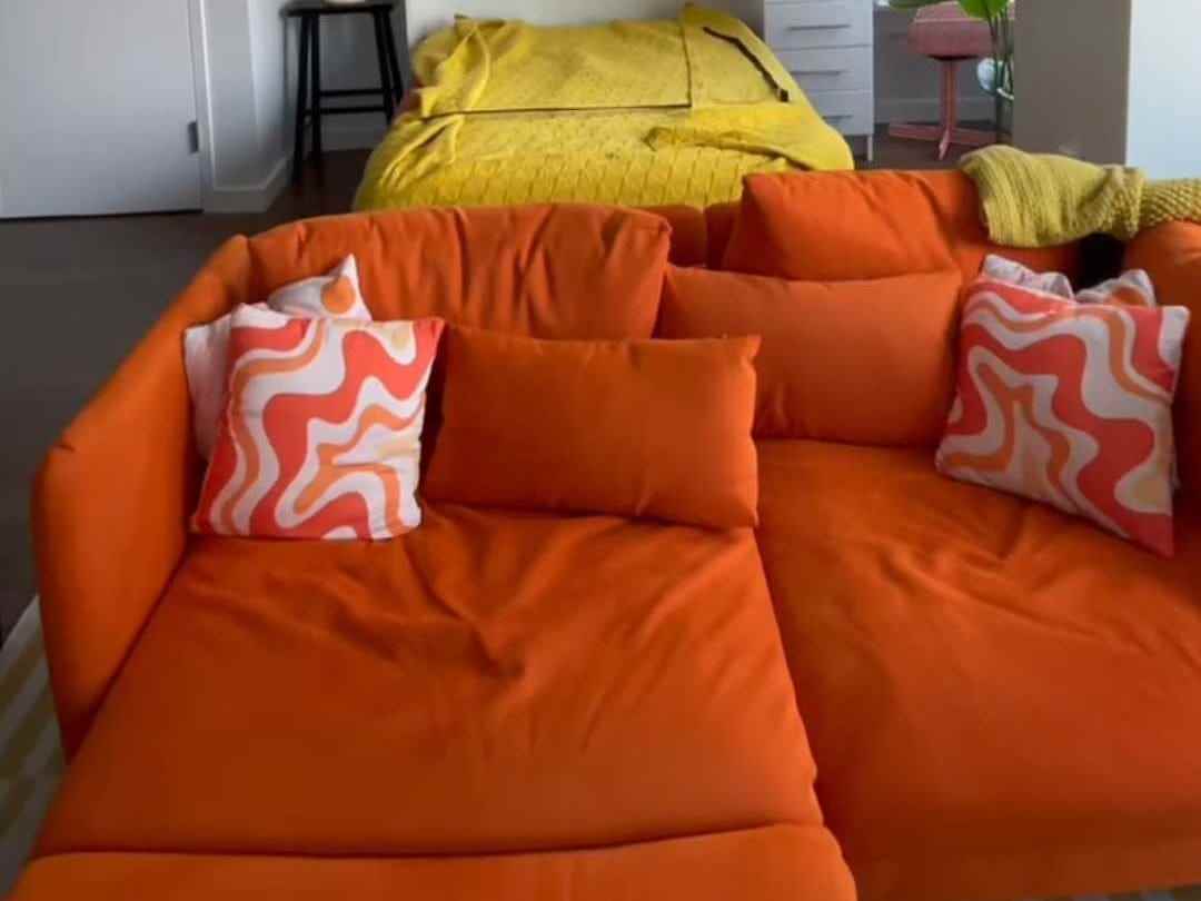 Eine orangefarbene Couch mit groovigen Kissen in Dunkelorange und Hellorange