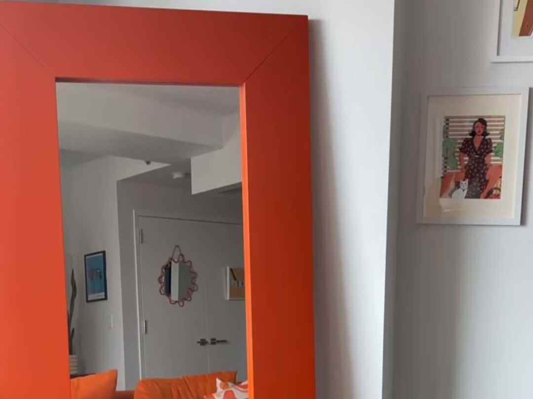 Ein großer, bodenlanger Spiegel mit einem orangefarbenen Rahmen
