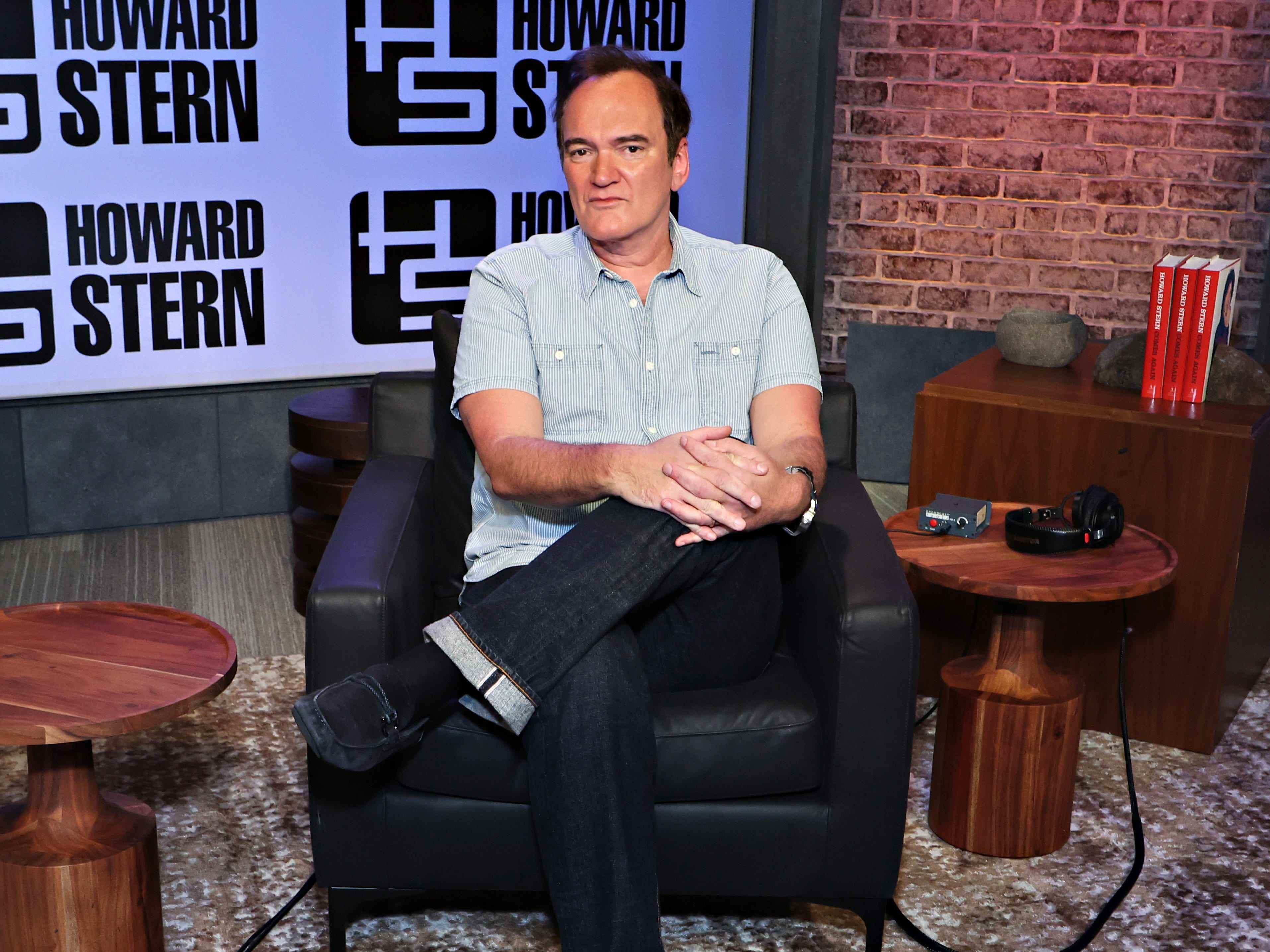 Quentin Tarantino sitzt mit gekreuzten Beinen auf einem Stuhl