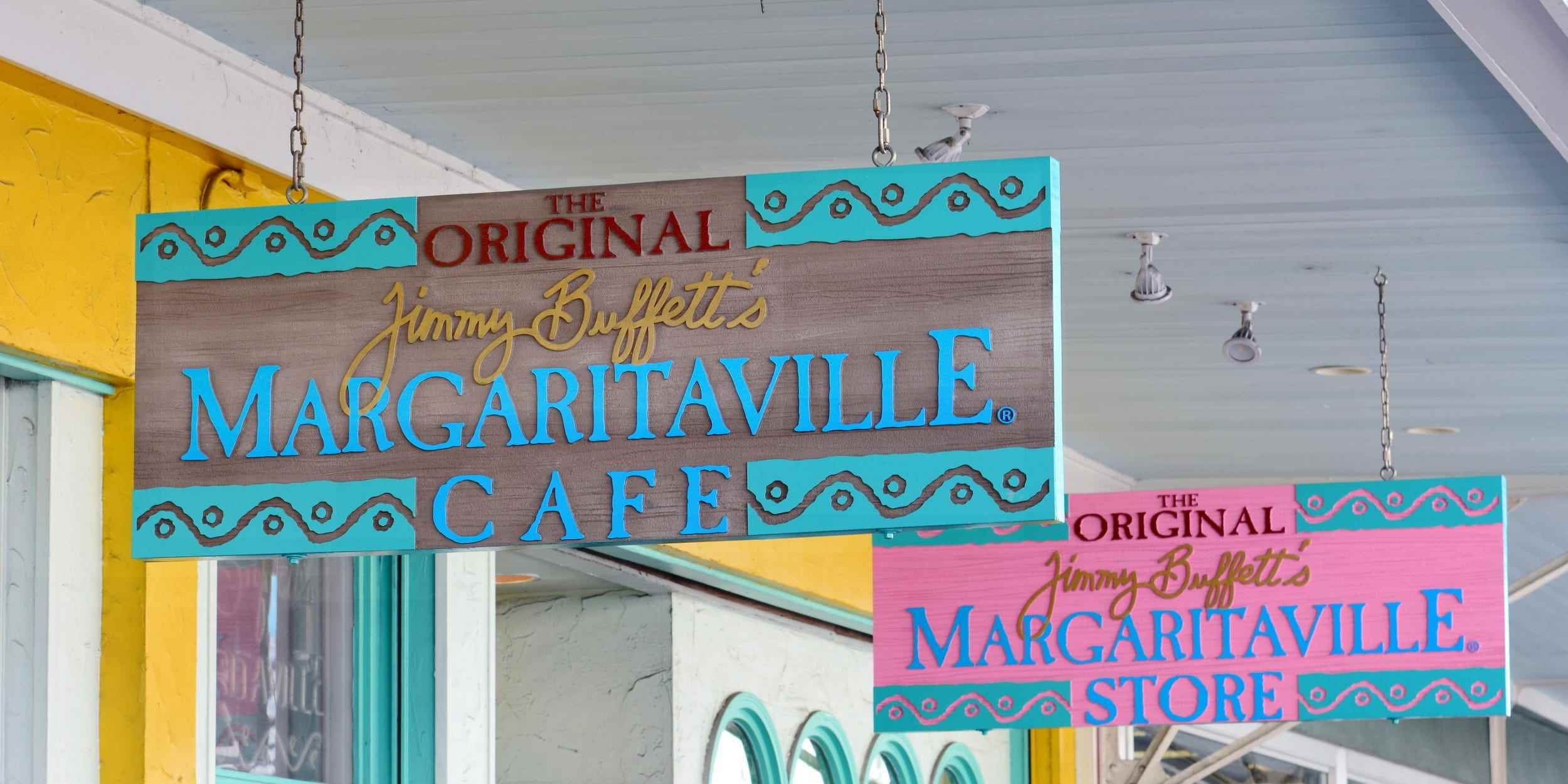 zwei an der Decke hängende Schilder mit der Aufschrift „The Original Jimmy Buffet’s Margaritaville Cafe“ und „The Original Jimmy Buffet’s Margaritaville Store“