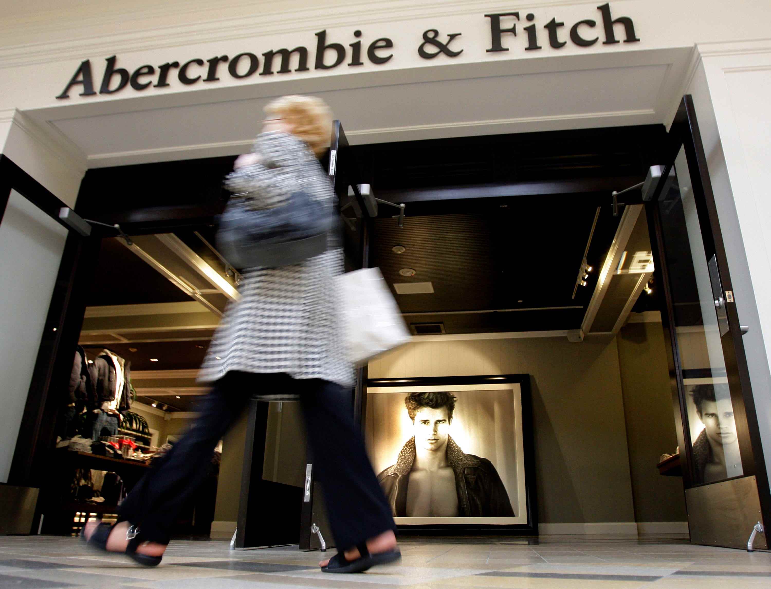 Shopper geht am Eingang zum Abercrombie & Fitch Store vorbei, auf dem das Foto des männlichen Models sichtbar ist