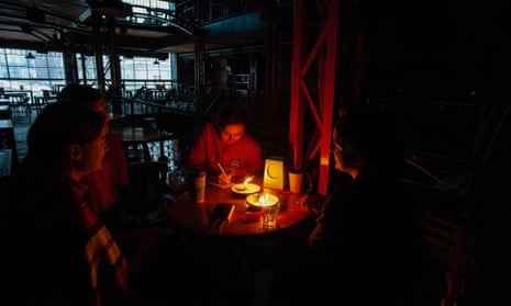 Menschen in einem mit Kerzen beleuchteten Restaurant in Lemberg, Ukraine, inmitten eines Stromausfalls