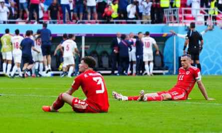 Ein niedergeschlagener Neco Williams und Gareth Bale sitzen nach der dramatischen und verheerenden Niederlage von Wales gegen den Iran auf dem Rasen.