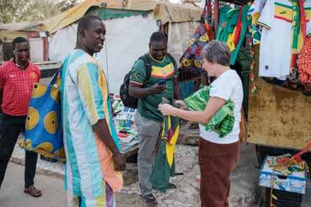 Eine Frau kauft ein senegalesisches Fußballtrikot von Ousseynou Thioune (Mitte links).