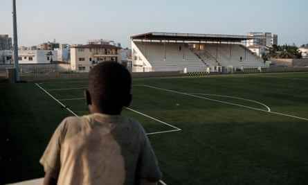 Ein kleiner Junge blickt über das Spielfeld eines Fußballstadions in einem Wohngebiet von Dakar.