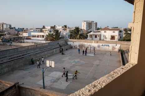 Auf einem Betonplatz in einem Wohngebiet von Dakar stellen Menschen kleine Tore auf, um Fußball zu spielen.