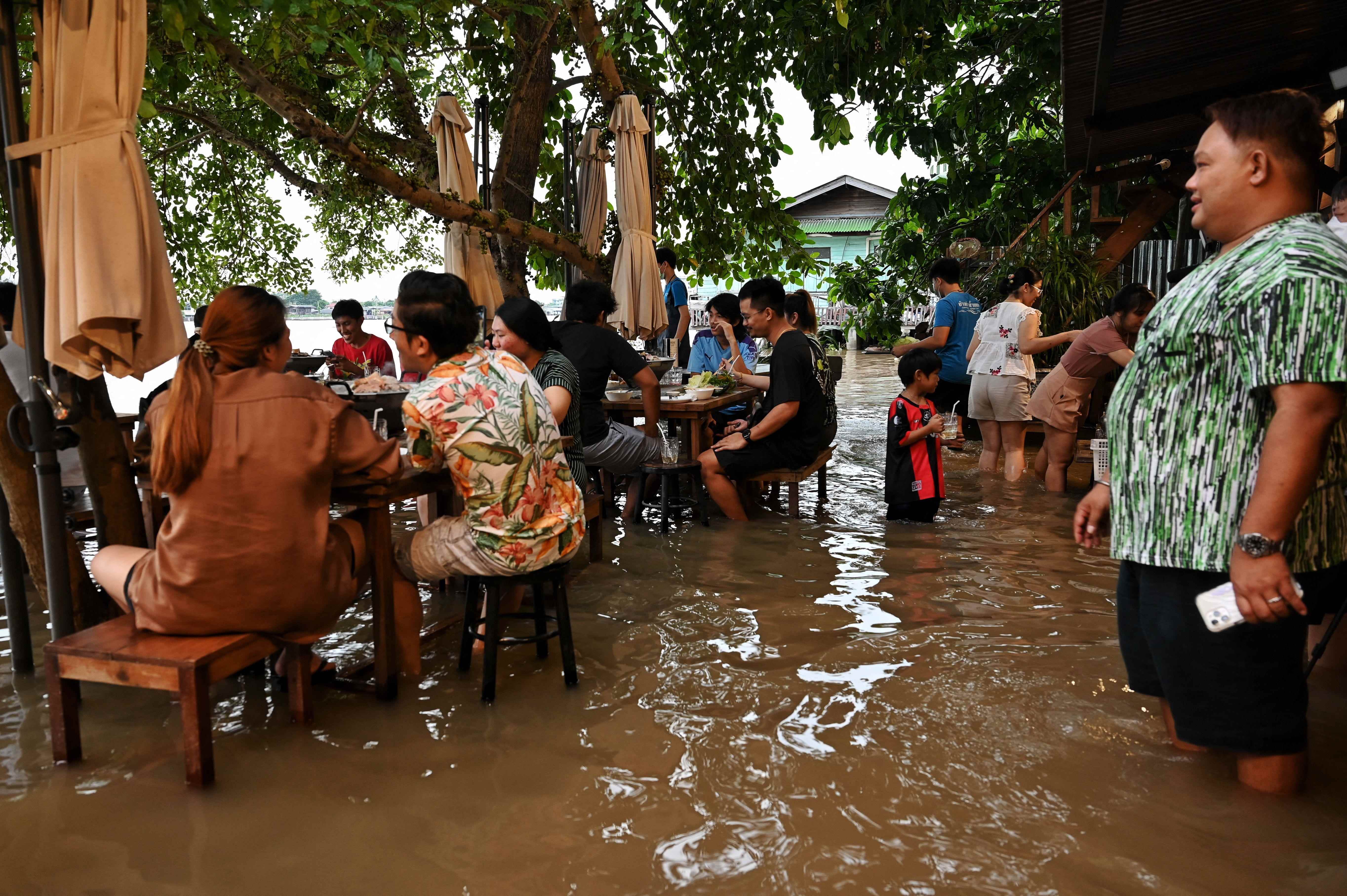 Dieses am 7. Oktober 2021 aufgenommene Foto zeigt Menschen, die im Chaopraya Antique Cafe zu Abend essen, während Hochwasser aus dem Fluss Chao Phraya in das Restaurant in der Provinz Nonthaburi nördlich von Bangkok strömt.