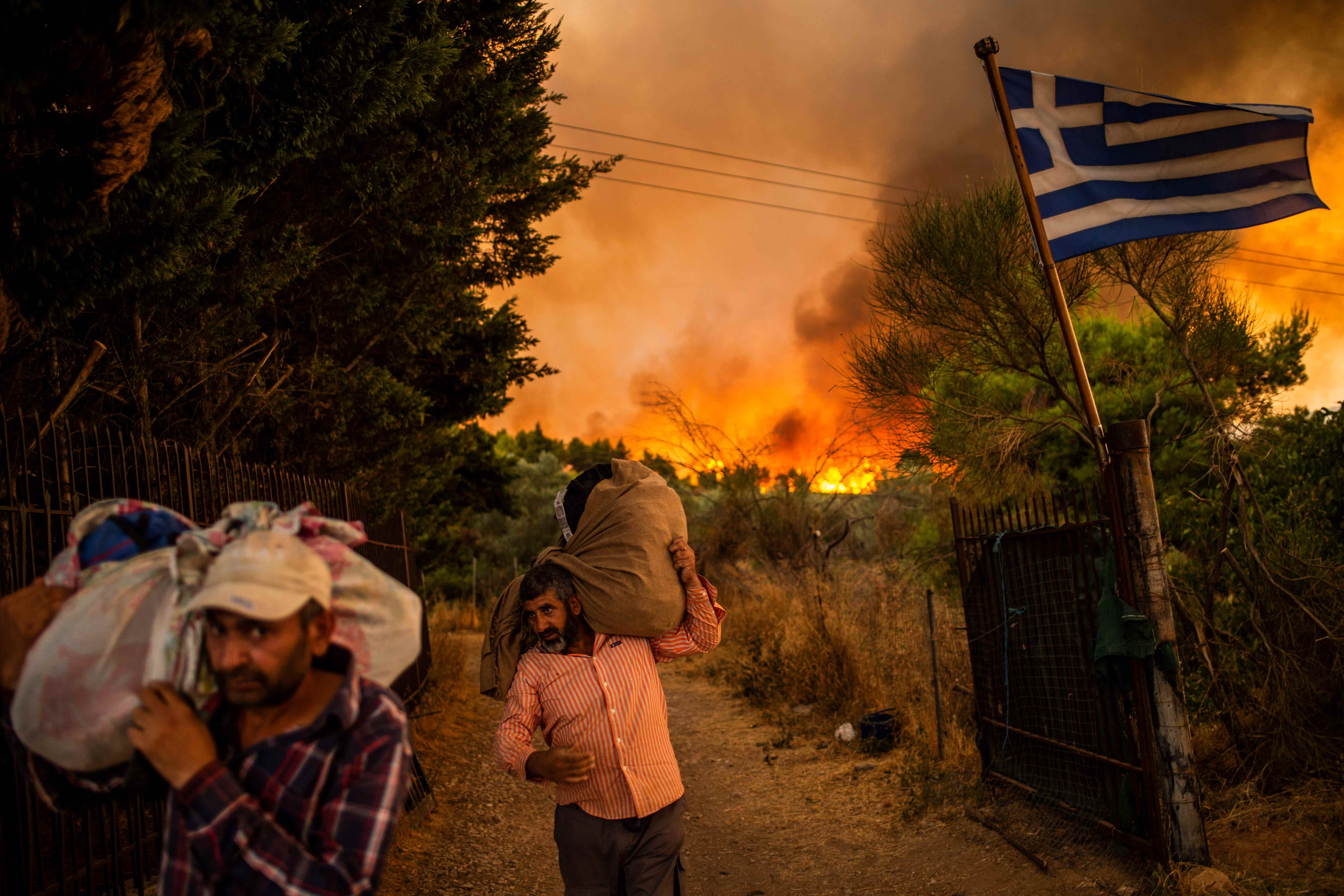 Menschen versuchen, Teile ihres Hab und Guts in Sicherheit zu bringen, während in einem Waldgebiet nördlich von Athen ein Waldbrand wütet.  Das Feuer nördlich von Athen ist am 05.08.2021 erneut aufgeflammt.