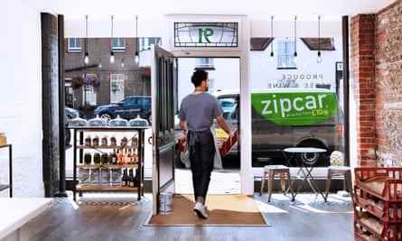 Mann, der eine Kiste mit Produkten vom Laden zum Zipcar-Van bringt