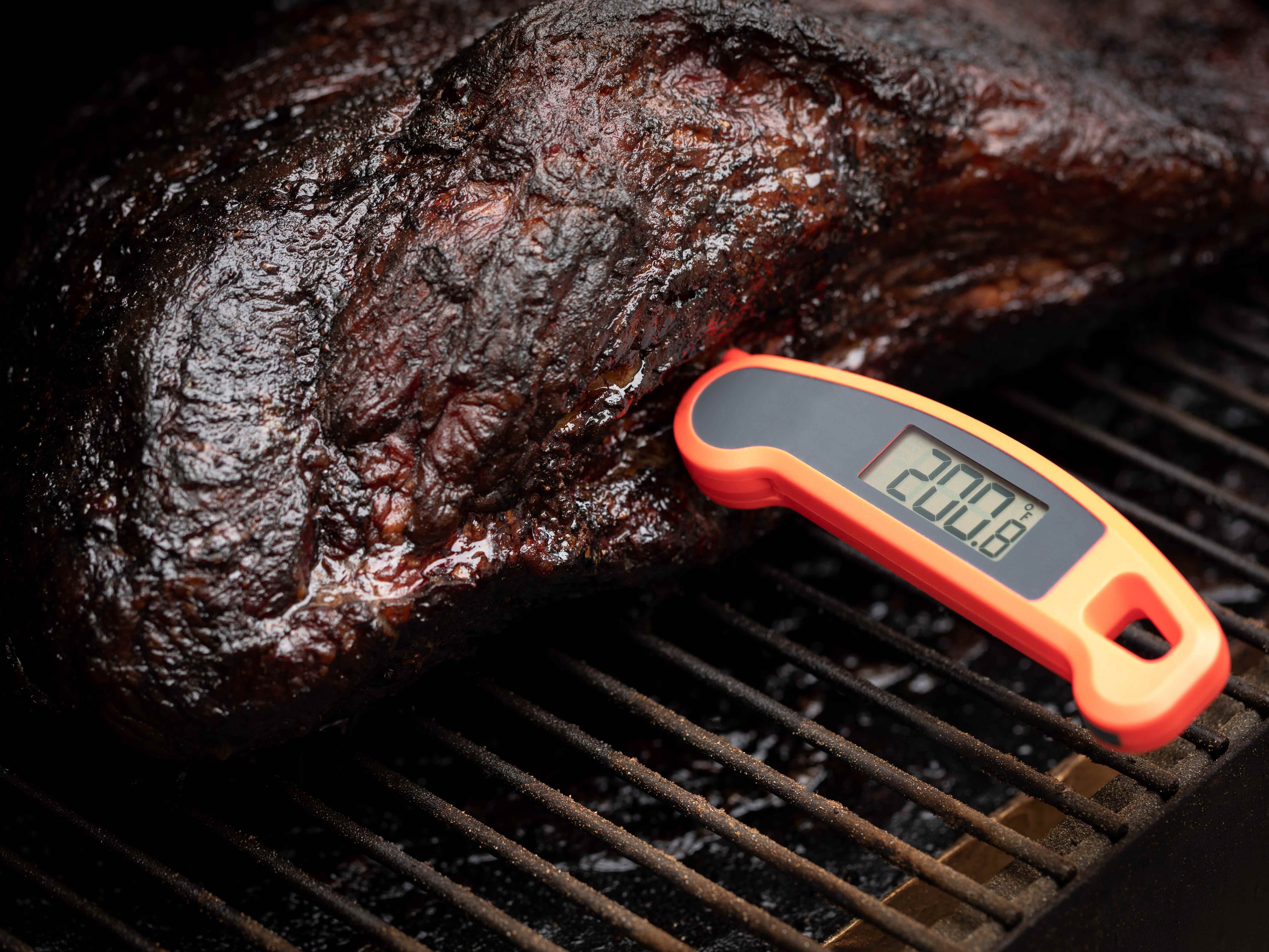 200-Grad-Fahrenheit-Thermometer in einer gekochten Rinderbrust auf den Grillrosten eines Räuchergrills