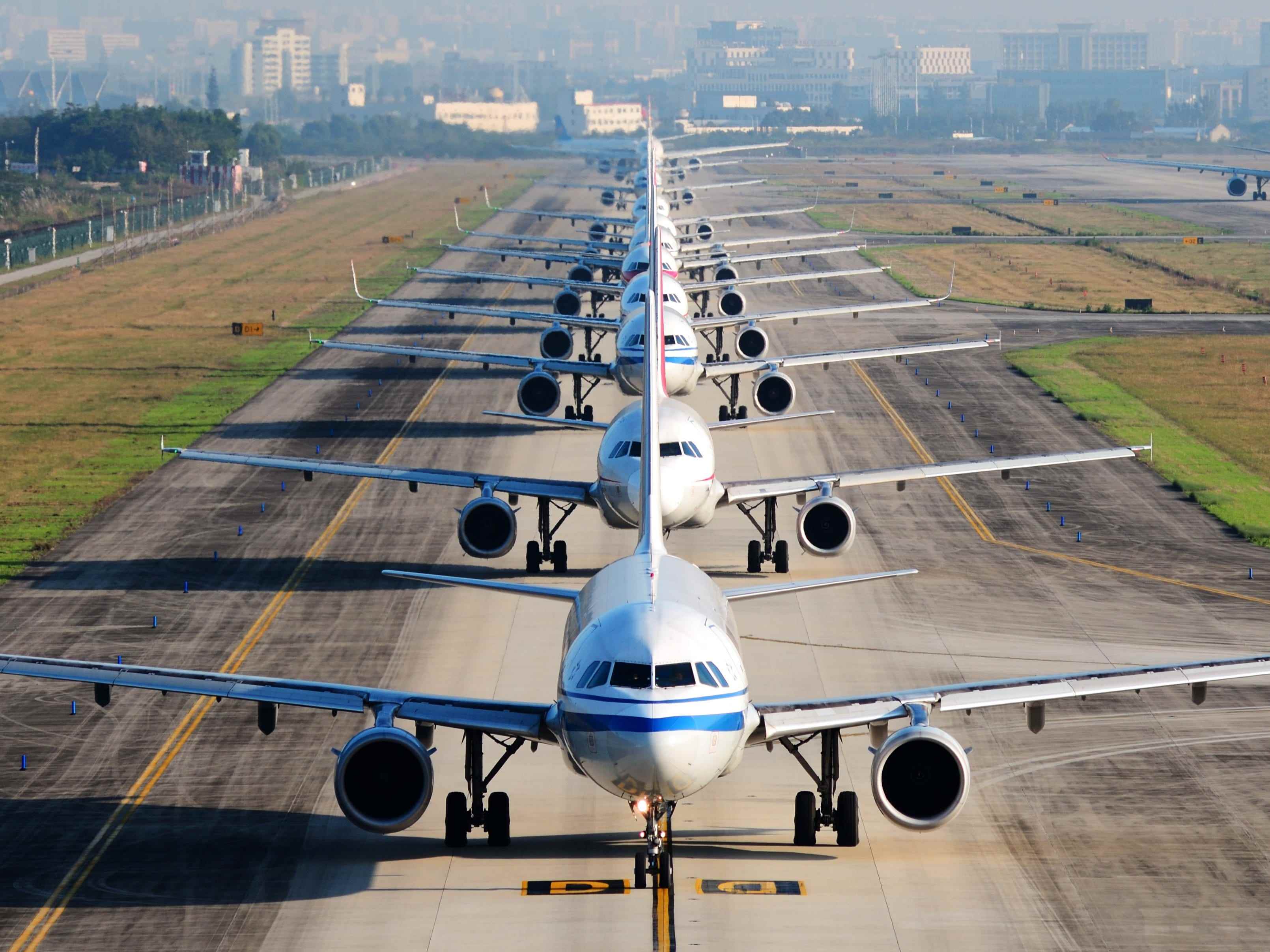 Eine Reihe von Flugzeugen auf der Landebahn, die auf den Start warten.