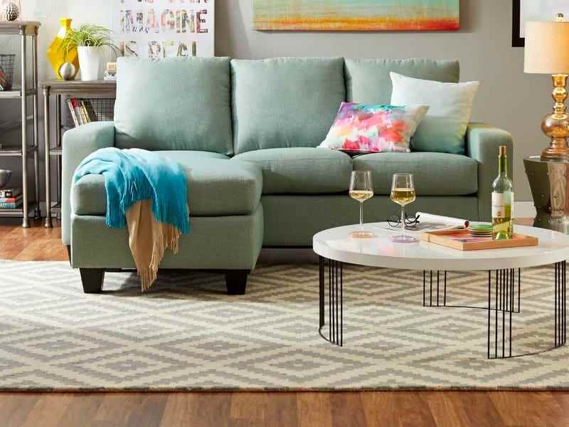 Bild eines weißen und grauen Wayfair-Teppichs mit Chevron-Muster unter einer blauen Couch und einem runden weißen Couchtisch für die besten Teppiche