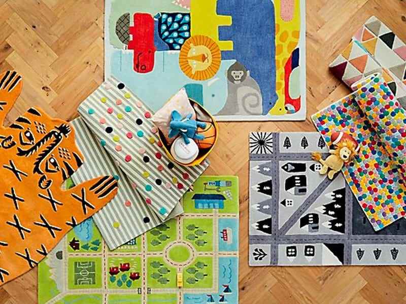 Bild von mehreren bunten Kisten- und Kinderteppichen, die auf einem Holzboden für die besten Teppiche zusammengestapelt sind
