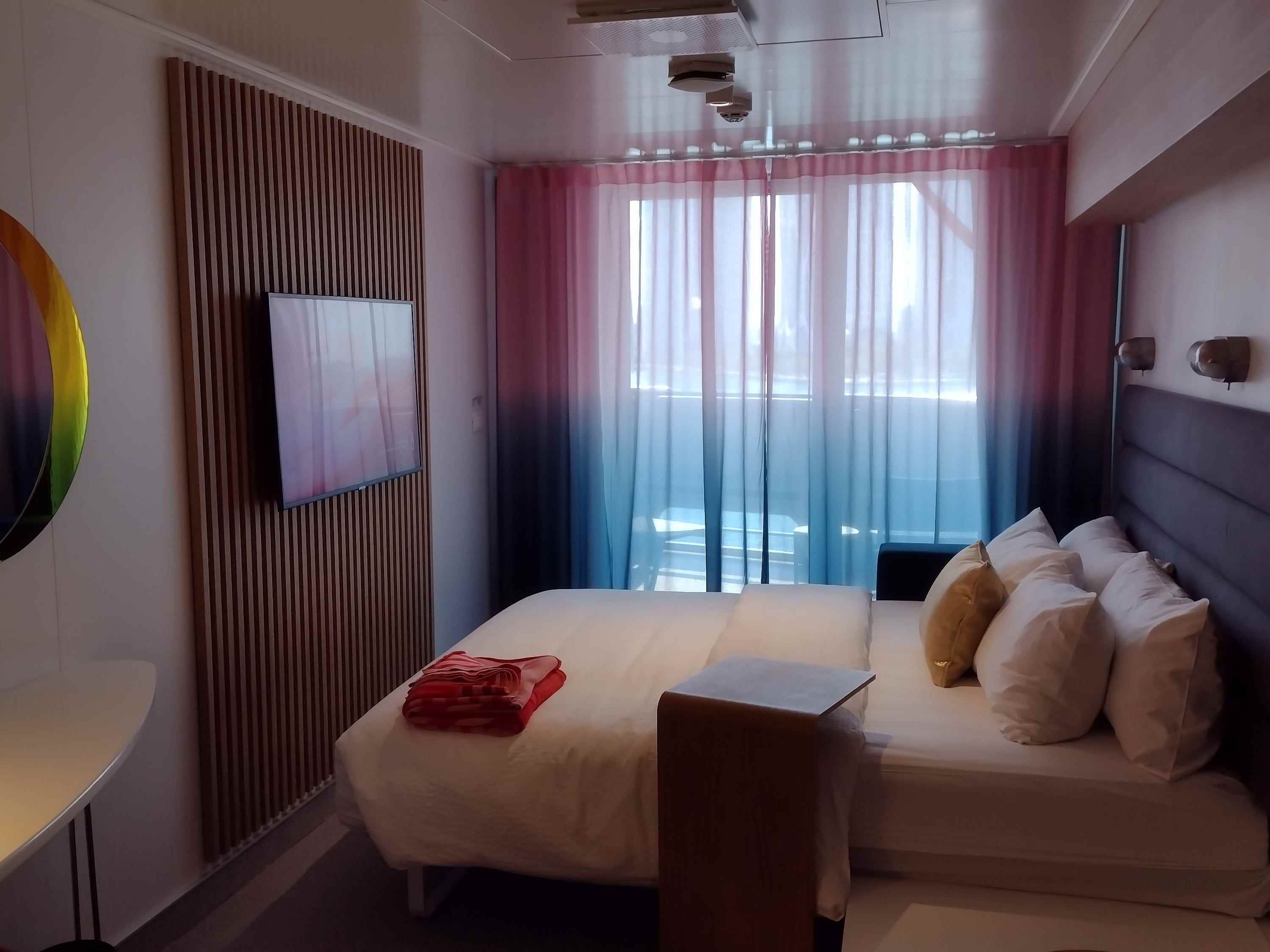 Eine Kreuzfahrtschiffskabine mit einem Bett und einem Balkon.