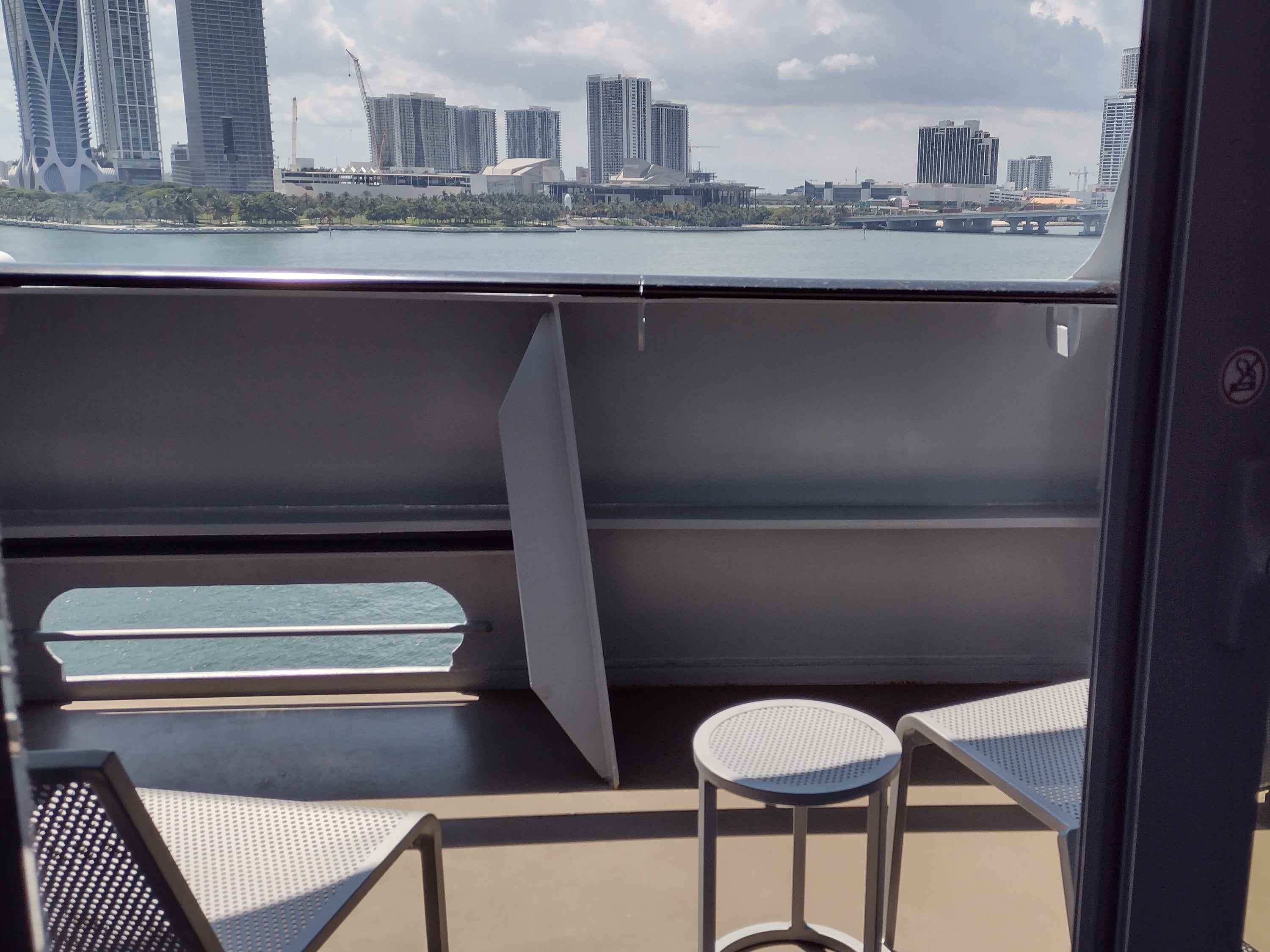 Ein Balkon auf einem Kreuzfahrtschiff mit zwei Stühlen und einem kleinen Tisch.