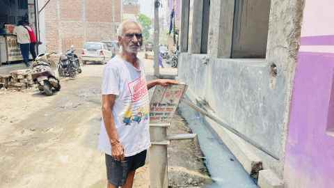 Jwala Prashad, 87, an der Handpumpe vor seinem Haus im Bhalswa Dairy Village.