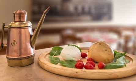Teig, Basilikum, Tomate und Mozzarella auf einem Brett mit Olivenölkrug