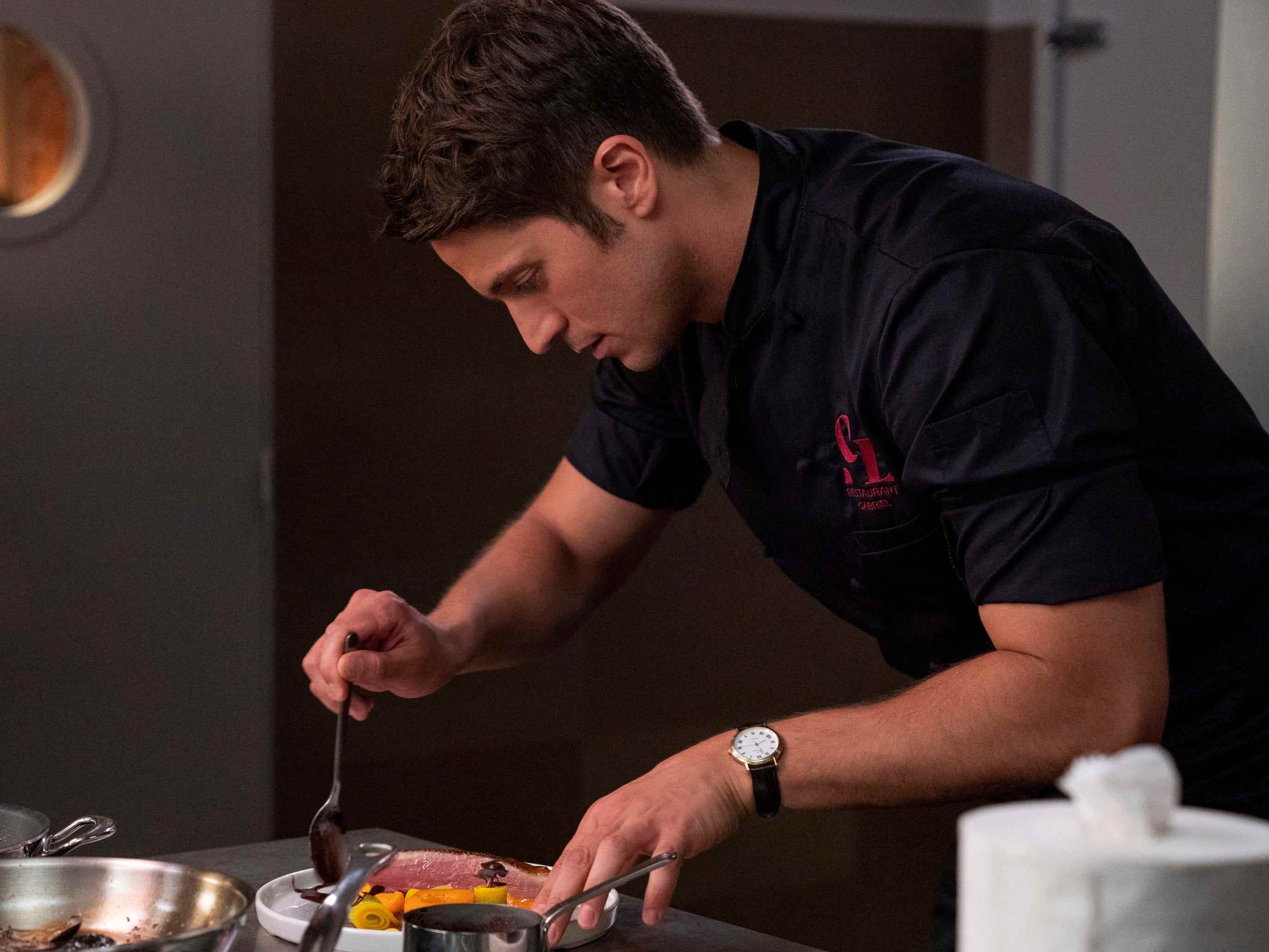 Gabriel bereitet in Staffel 2 von Emily in Paris einen Teller in seinem Restaurant zu