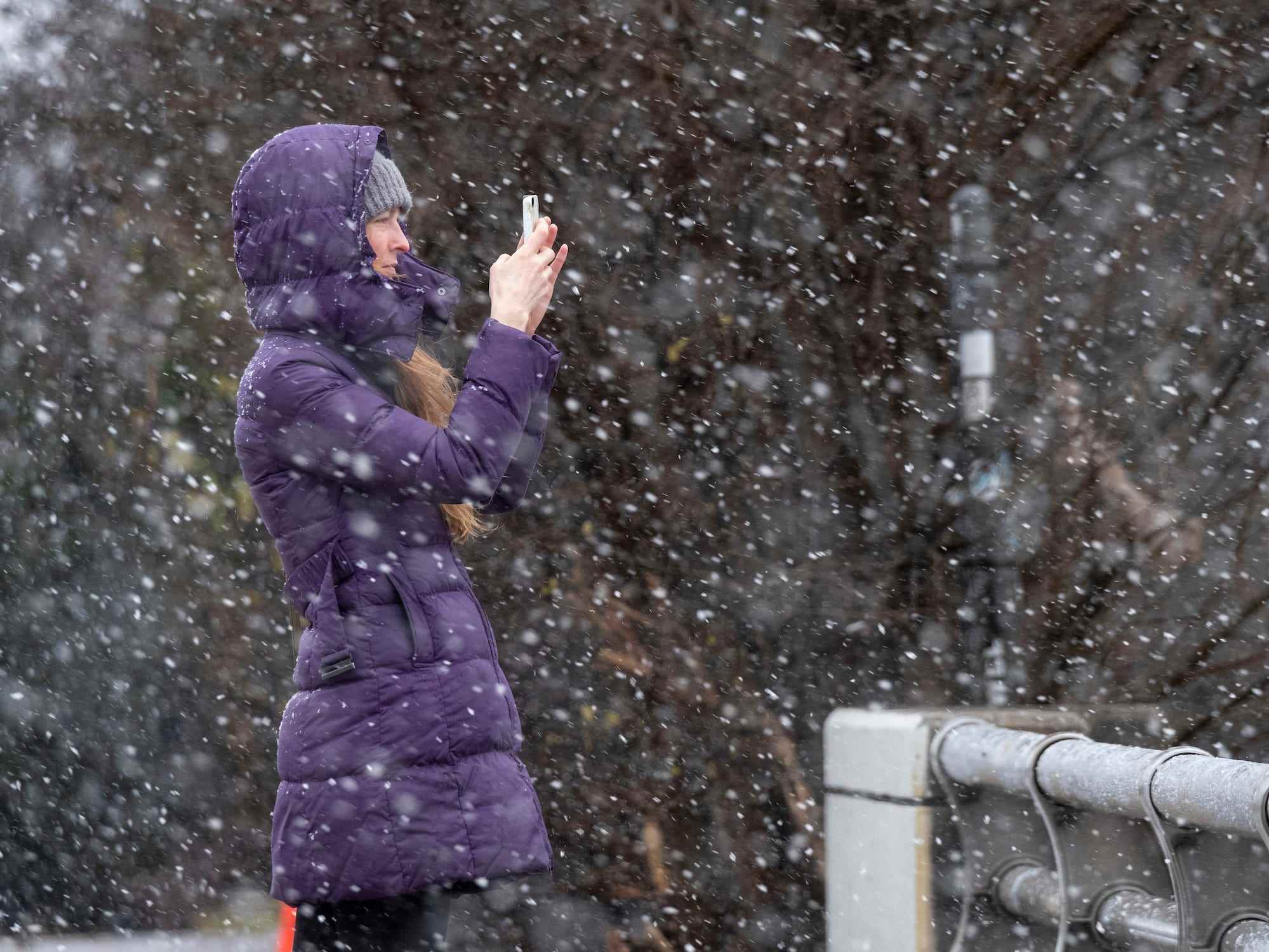 Bridget Step hält an, um ein Foto des Schnees zu machen, während sie den Schneefall in Atlanta beobachtet, während ein Wintersturm am Sonntag, 16. Januar 2022, in die Gegend rollt.