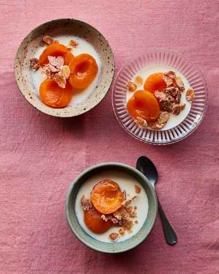 Drei Schalen pochierte Aprikosenhälften mit Mandelcreme auf einer rosa Tischdecke.