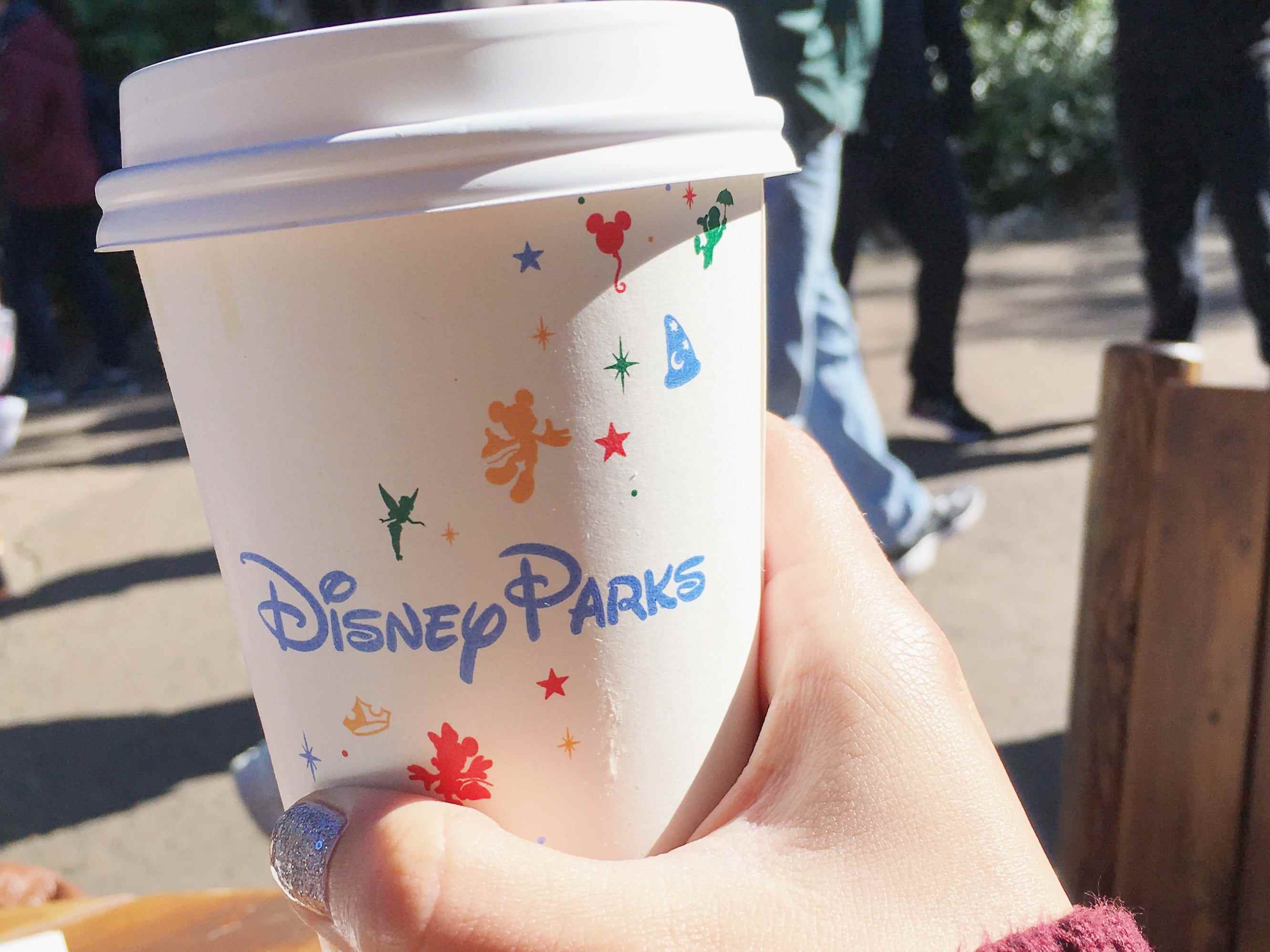 Hand, die Kaffee in einem Disney-Einwegbecher hält