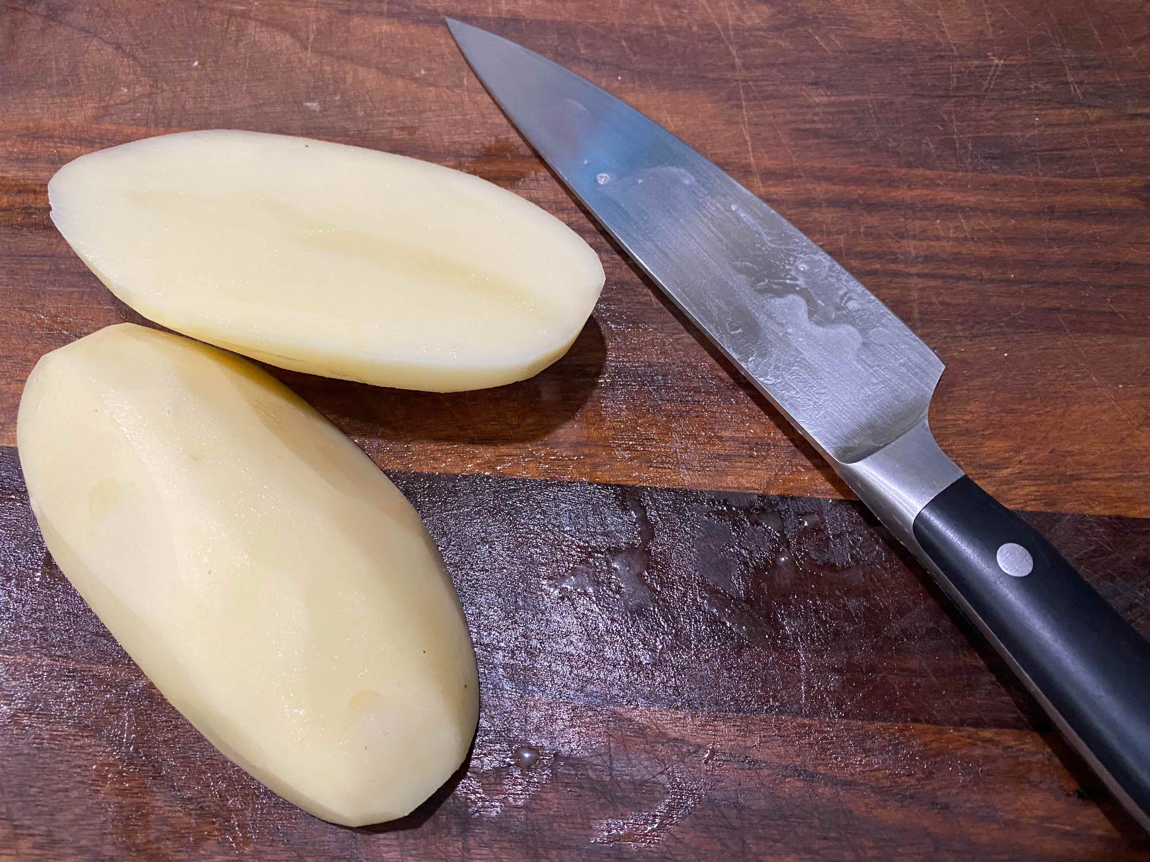 Kartoffel halbiert auf einem Schneidebrett neben einem Messer