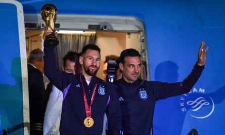 Lionel Messi hält die Weltmeisterschaft, flankiert von Argentiniens Trainer Lionel Scaloni, als sie in Buenos Aires aus dem Flugzeug steigen.