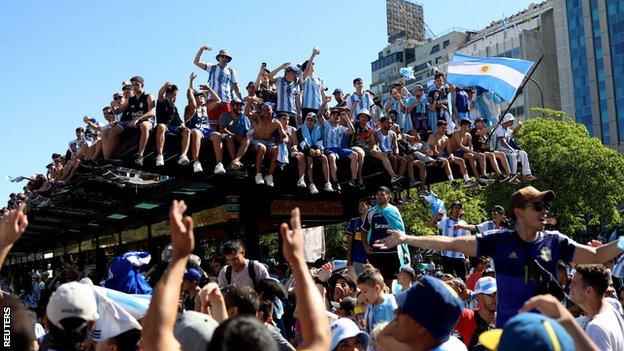 Argentinien-Fans klettern auf ein Busdach auf der Plaza de la República in Buenos Aires, während sie auf die Ankunft des Teams warten
