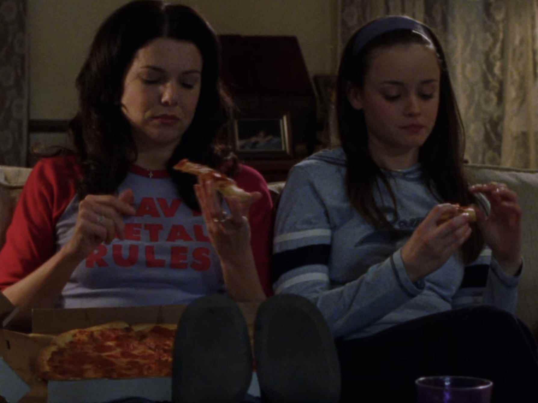 Lorelai und Rory sitzen auf der Couch und essen Pizza auf Gilmore Girls