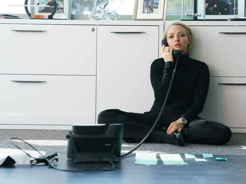 Amanda Seyfried in schwarz gekleidet am Telefon auf dem Boden sitzend