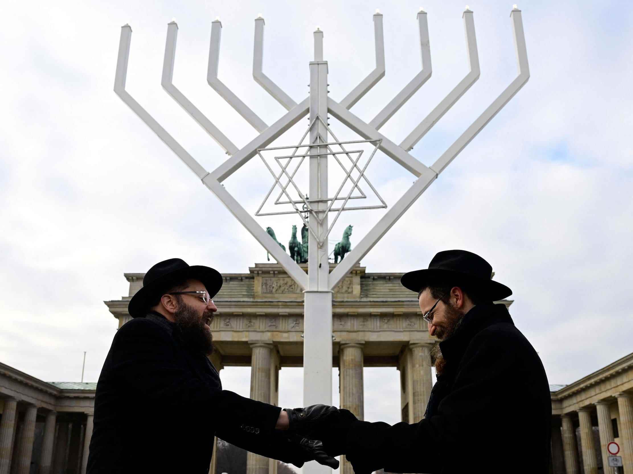 Die Rabbiner Yehuda Teichtal (L) und Shmuel Segal singen und tanzen, während sie vor dem Brandenburger Tor eine riesige Menora weihen