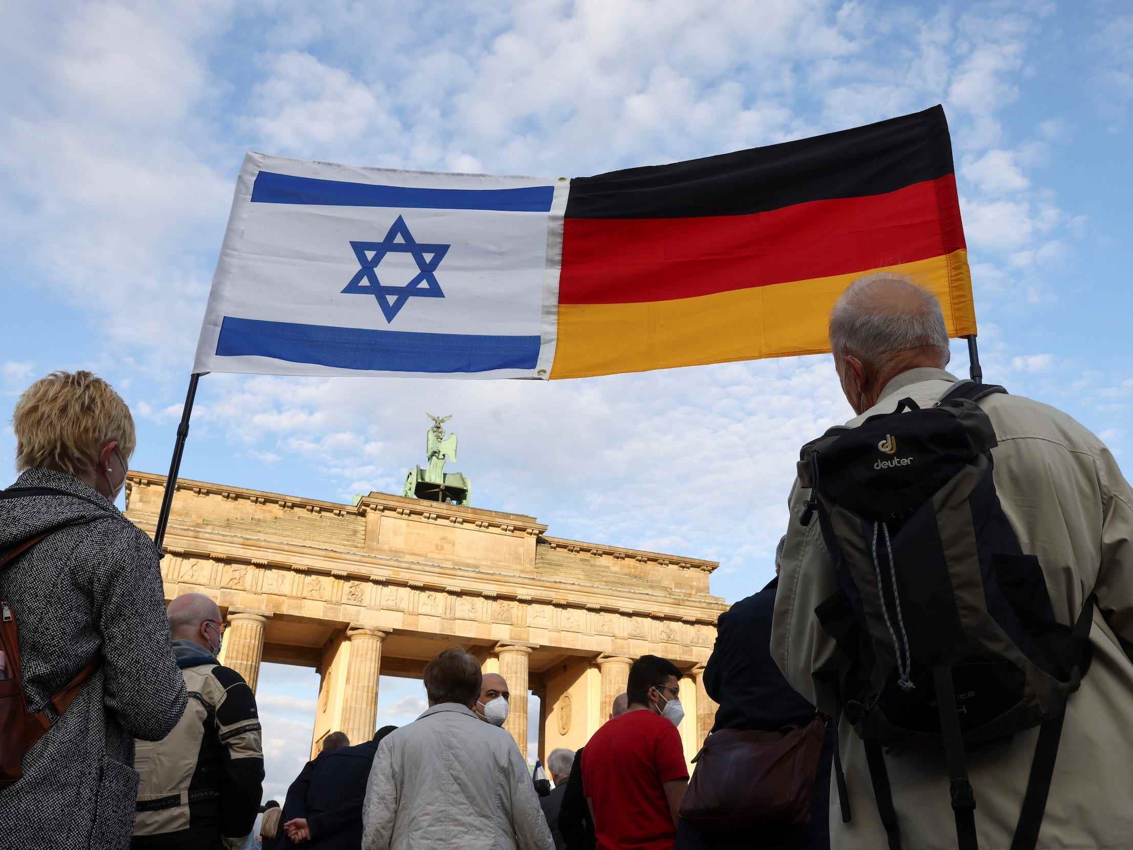 Menschen tragen während einer Kundgebung eine israelische und eine deutsche Flagge