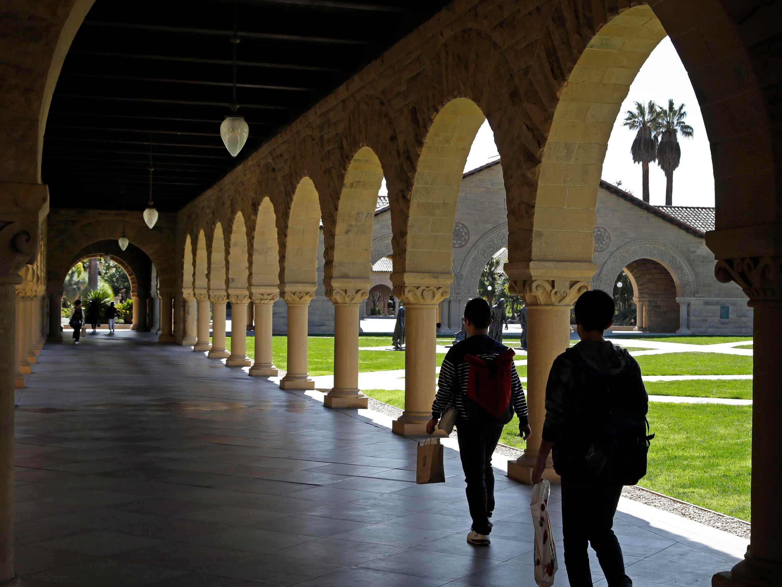 Passanten neben Säulen und Bögen auf dem Campus der Stanford University.