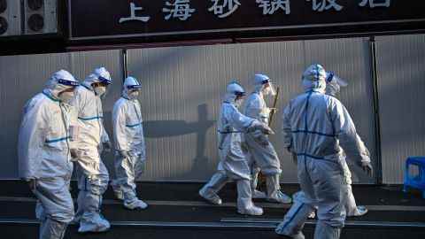 Arbeiter in Schutzkleidung gehen an Barrieren vorbei, die aufgestellt wurden, um Straßen in Gebieten zu sperren, die nach der Entdeckung von Fällen von Covid-19 in Shanghai am 15. März 2022 gesperrt wurden.