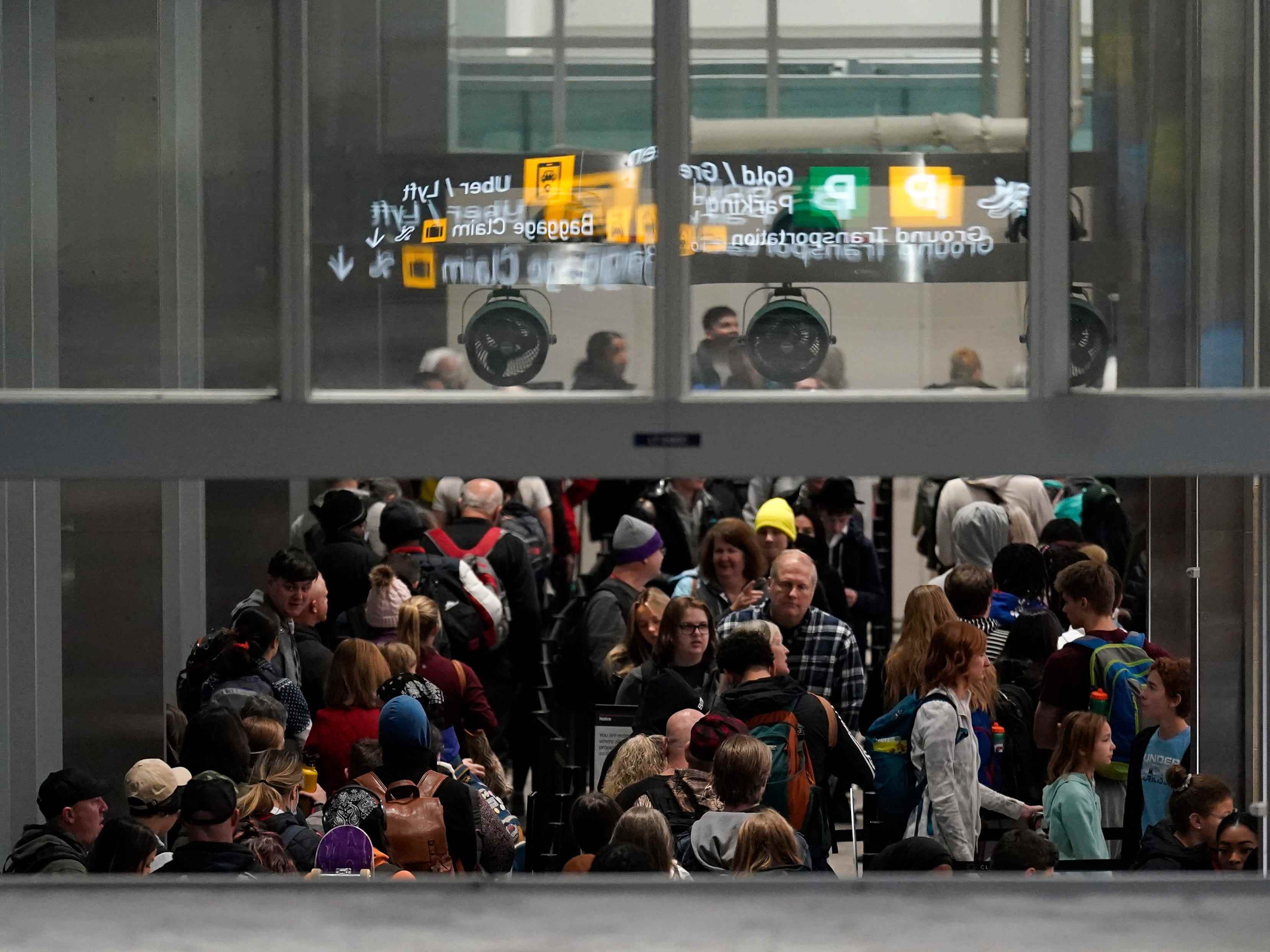 Reisende warten in Terminal 1 am Flughafen Minneapolis St. Paul am Mittwoch, 21. Dezember 2022, in Minneapolis in der Schlange, um die Sicherheitskontrolle zu passieren.