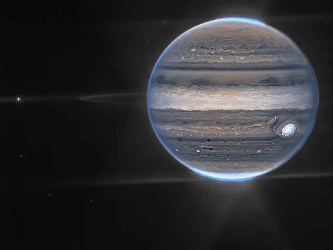 Weitfeldansicht von Jupiter, aufgenommen von Webb.  Die unscharfen Flecken im unteren Hintergrund sind wahrscheinlich Galaxien.