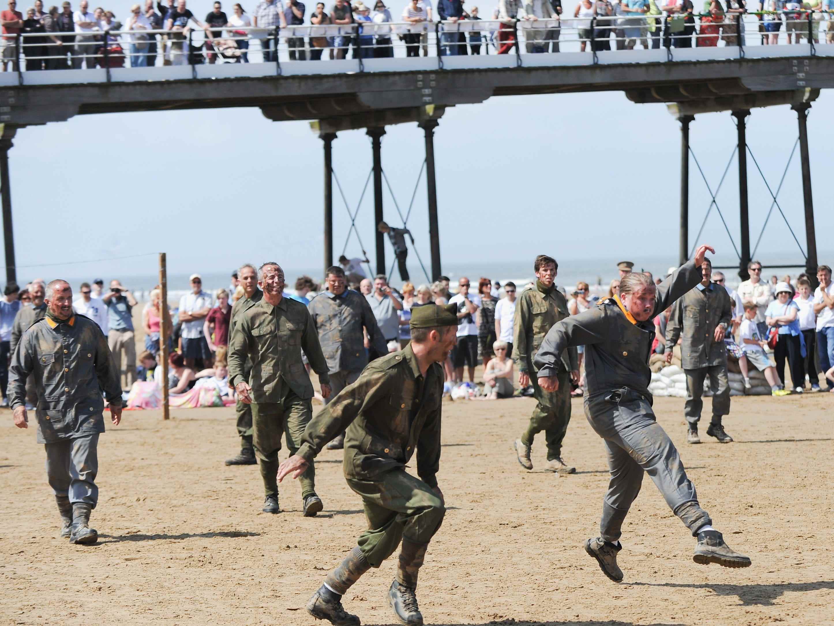 e-encators, die die britische und die deutsche Armee spielen, spielen Fußball während einer Gedenkveranstaltung, um an das Waffenstillstands-Fußballspiel des Ersten Weltkriegs am 1. Juni 2014 in Saltburn-by-the-Sea, England, zu erinnern.