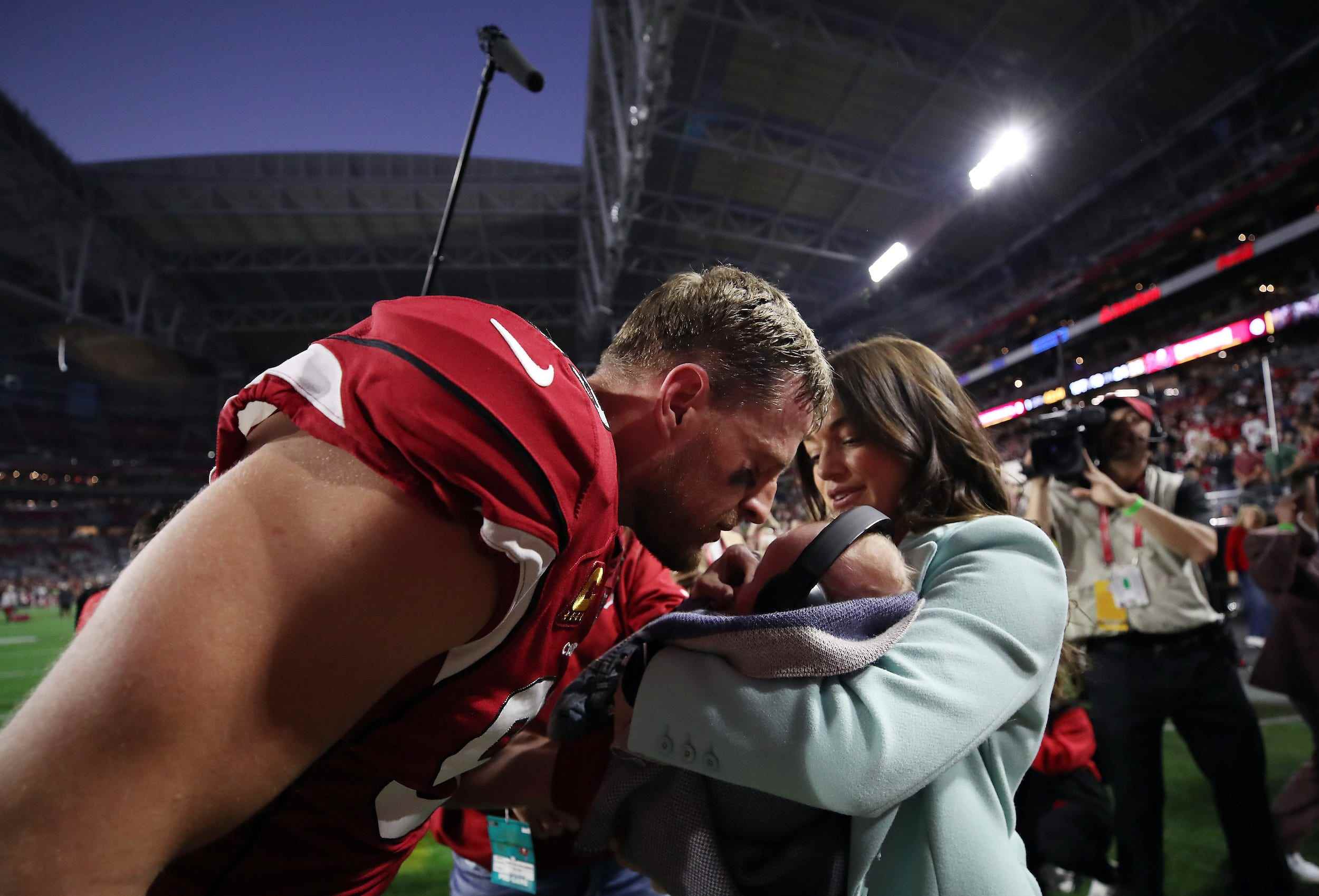 Kealia und JJ Watt umarmen ihren zwei Monate alten Sohn Koa nach einem Heimspiel der Arizona Cardinals.