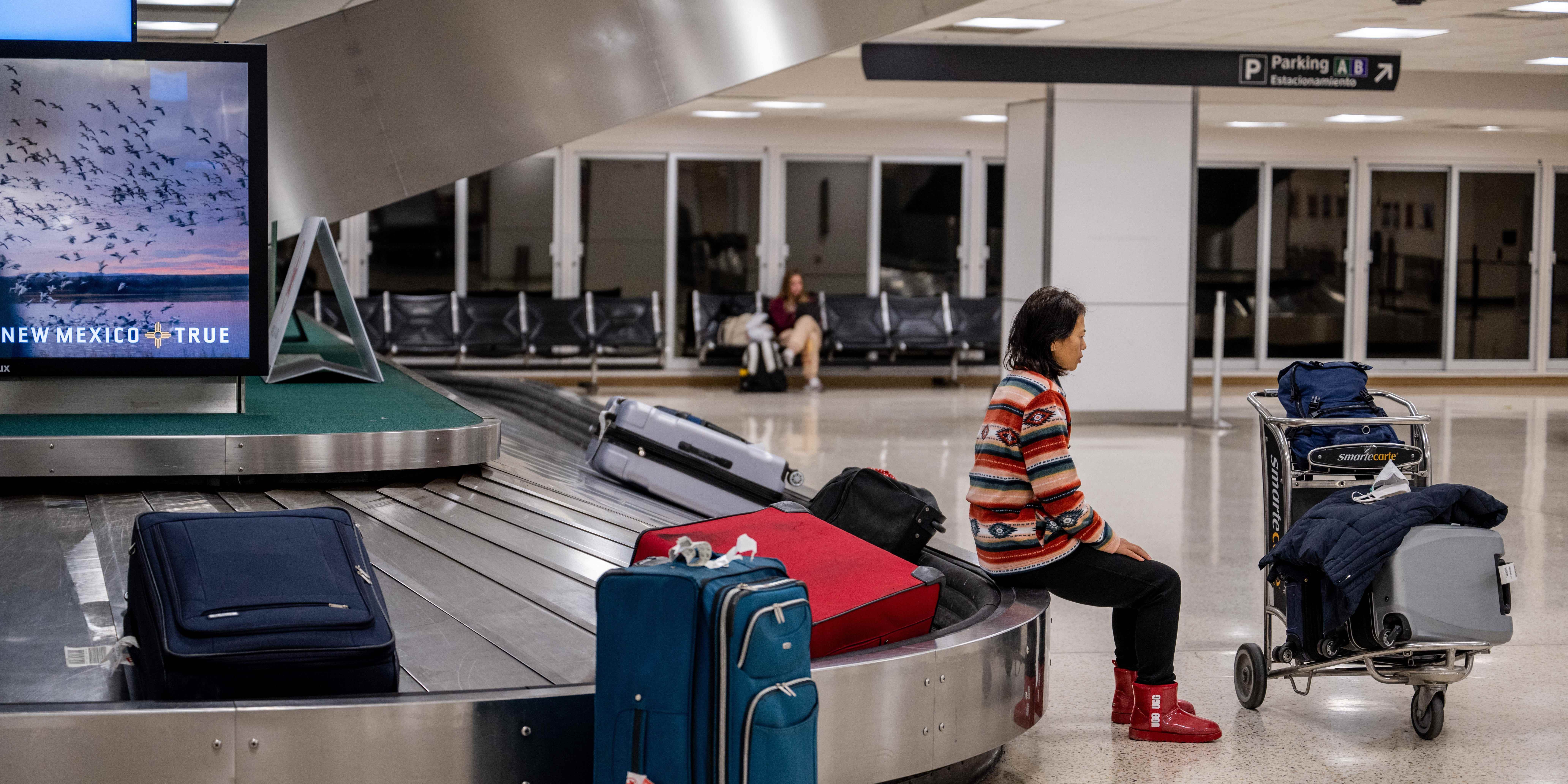 Ein Reisender sitzt am 27. Dezember 2022 in Houston, Texas, auf dem Gepäckausgabeband am George Bush Intercontinental Airport.