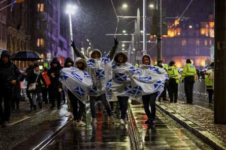 Menschen warten im Regen auf die Neujahrsfeierlichkeiten in Edinburgh.