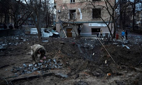 Ein ukrainischer Soldat sammelt Raketensplitter in einem Krater, den ein russischer Angriff neben einem Wohnhaus in Kiew hinterlassen hat