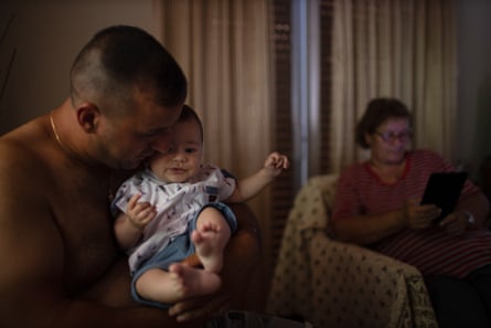 Kostas spielt mit seinem Baby, während sich seine Mutter Georgia auf dem Sofa entspannt