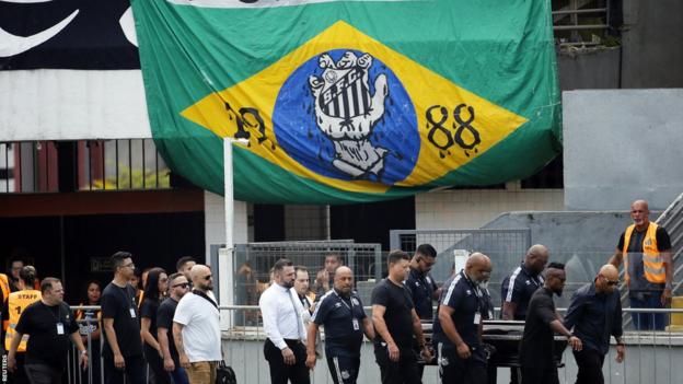 Peles Sarg wird vor einer brasilianischen Flagge getragen