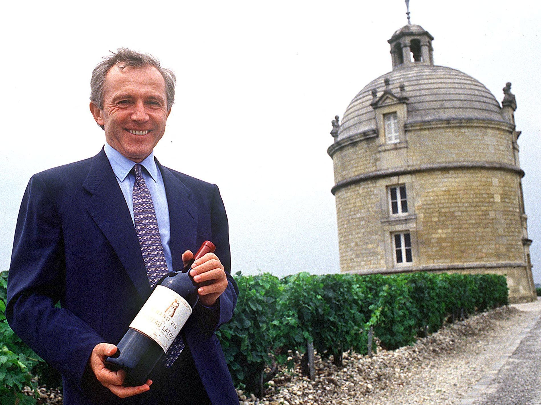 François Pinault hält eine Flasche Wein vor dem Weingut Chateau Latour
