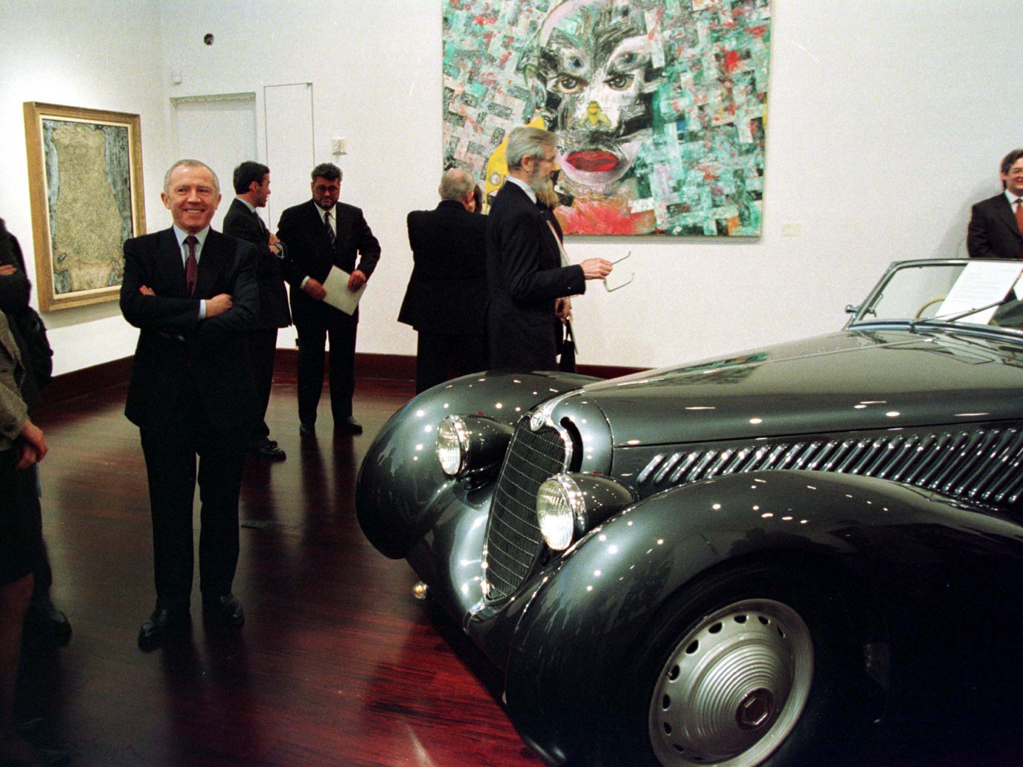 Francois Pinault posiert neben einem Oldtimer im Auktionshaus von Christie's